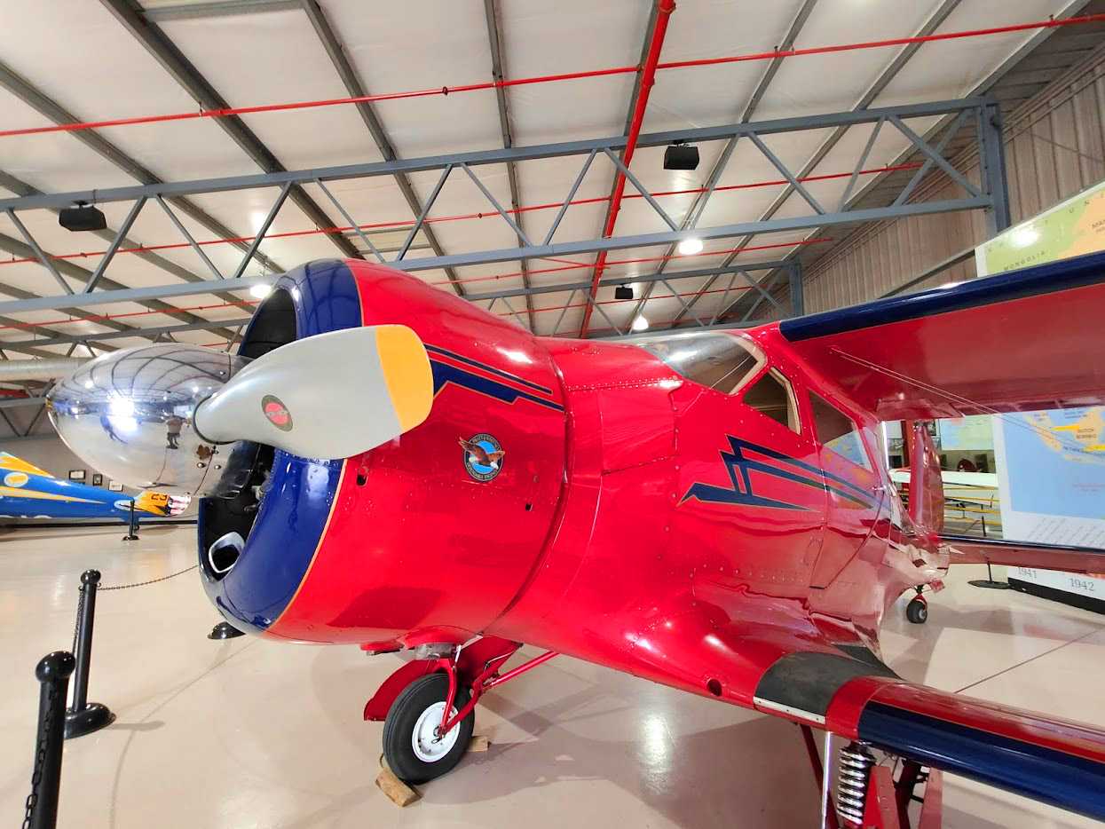 Red vintage aircraft displayed inside a Planes of Fame Air Museum hangar in Chino