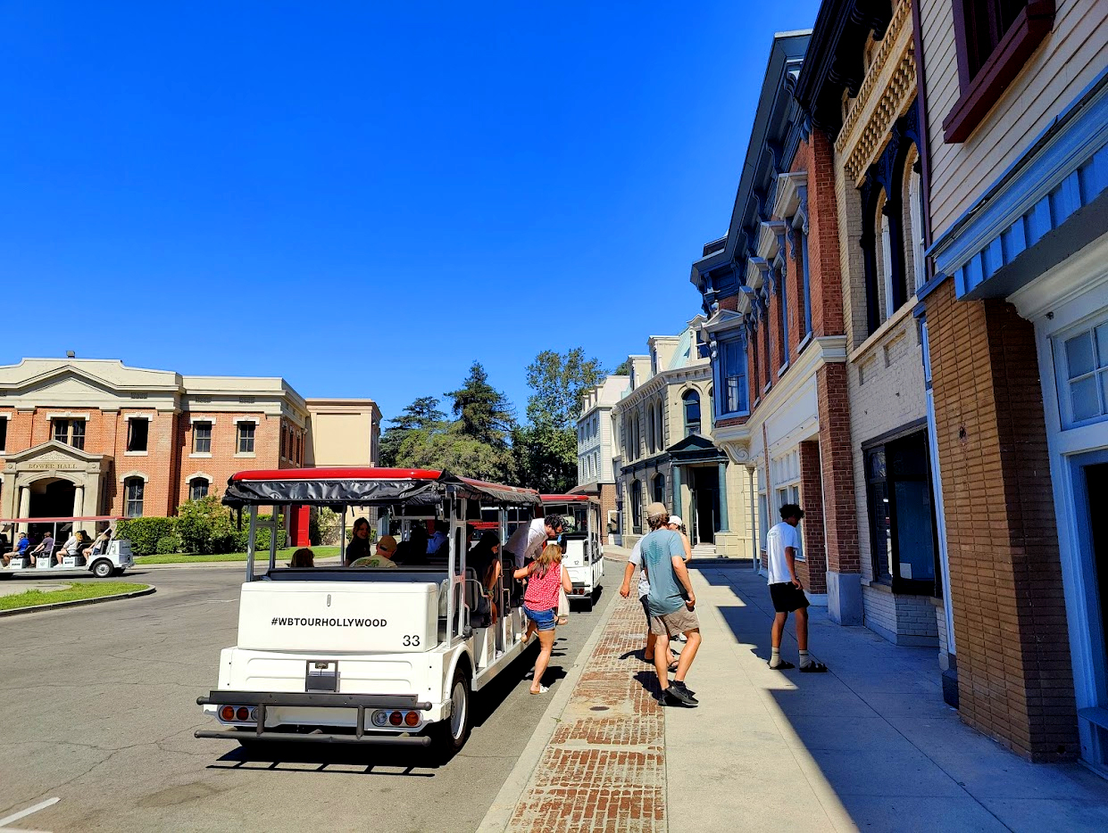 Studio tour electric tram navigating backlot streets and production soundstages